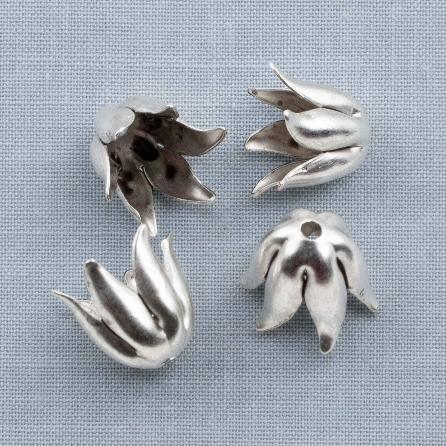 Hackberry Creek antique silver-plated pewter curled petal bead caps for 8mm jewelry beads on a grey fabric background