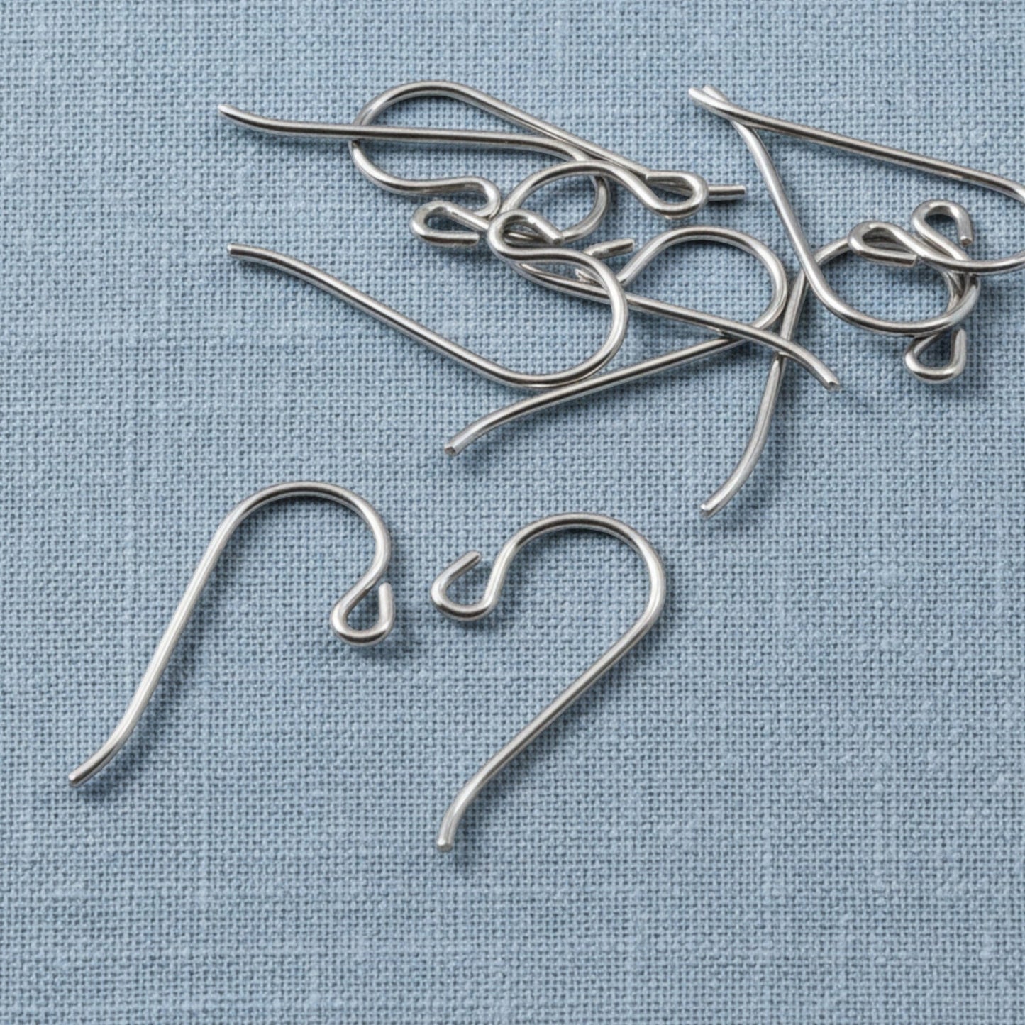 Hackberry Creek hypoallergenic gray niobium French hook ear wires with small loops on a blue fabric background.
