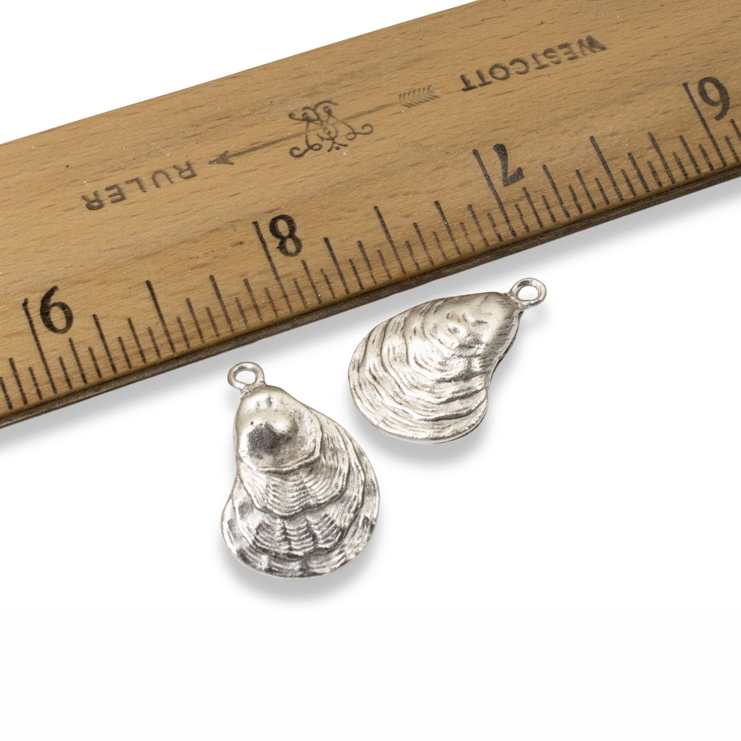 Hackberry Creek antique silver oyster shell charms for jewelry making, shown with a ruler for scale.