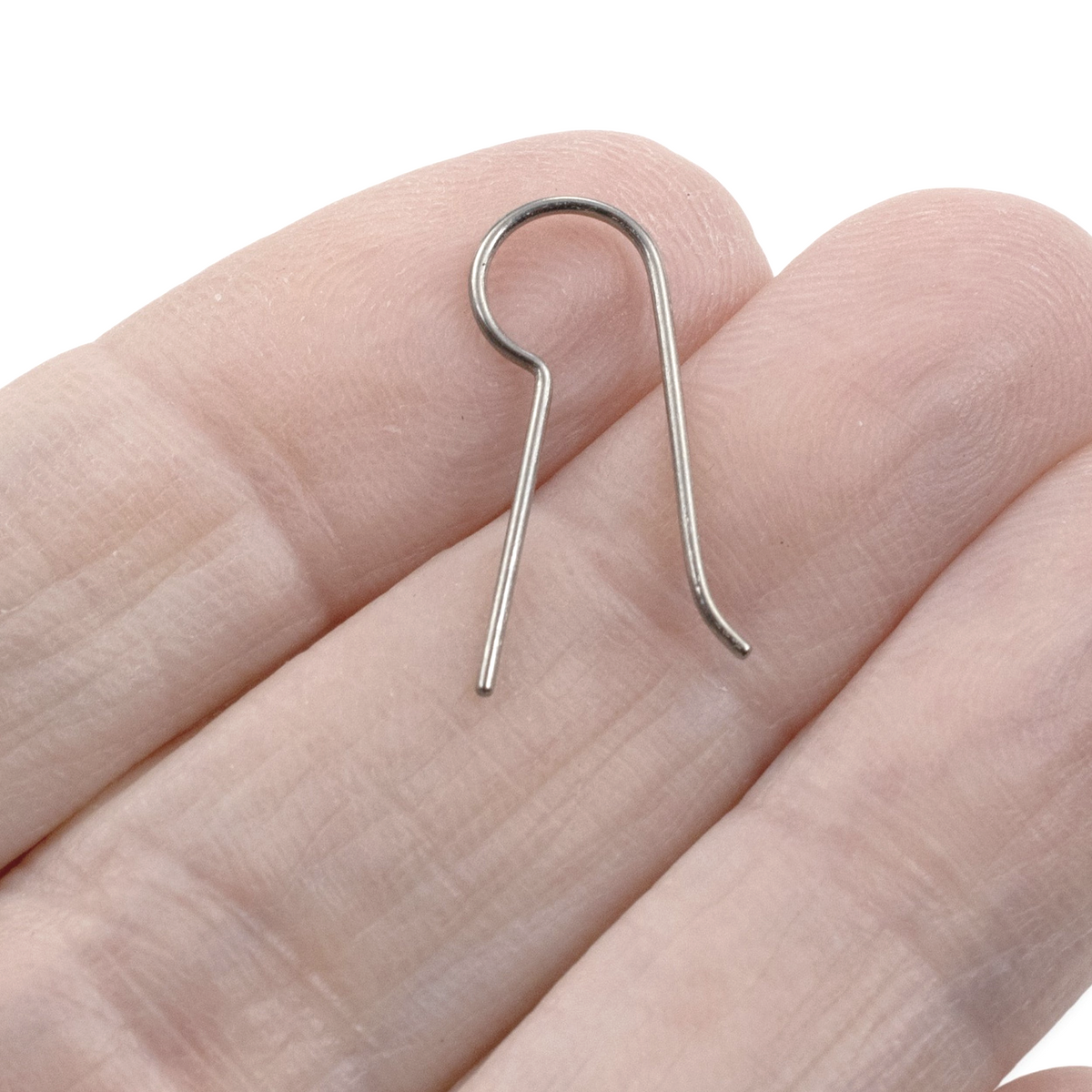 Hackberry Creek titanium ear wire blank with a straight leg for custom jewelry making on a person's finger