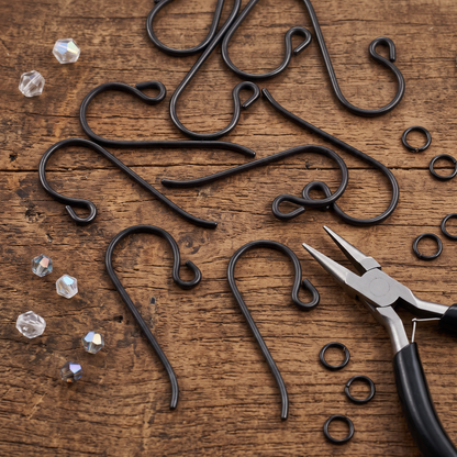 Hackberry Creek black niobium French hook ear wires with small loops and jewelry pliers on a rustic wooden surface.