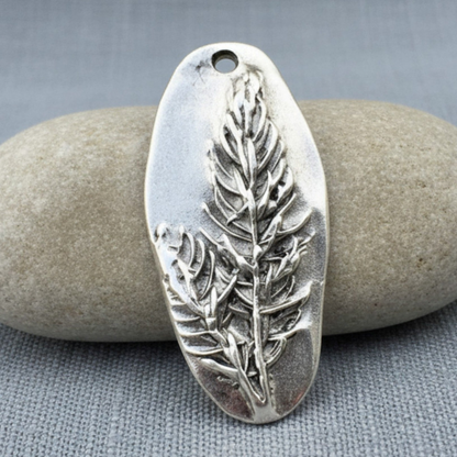 Hackberry Creek antique silver Denali pine tree pendant with detailed forest design on a smooth grey stone background