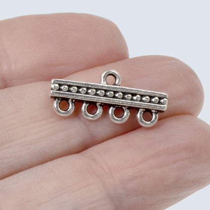 Hackberry Creek silver-plated pewter 4-to-1 beaded connector link held between fingers for jewelry making