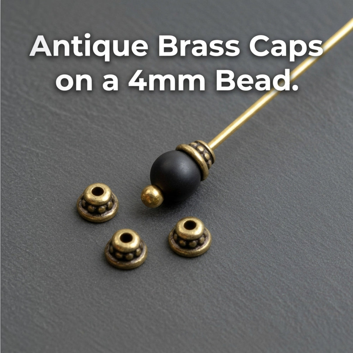 Hackberry Creek antique brass beaded bead caps shown on a headpin with a black bead and loose on a dark surface.