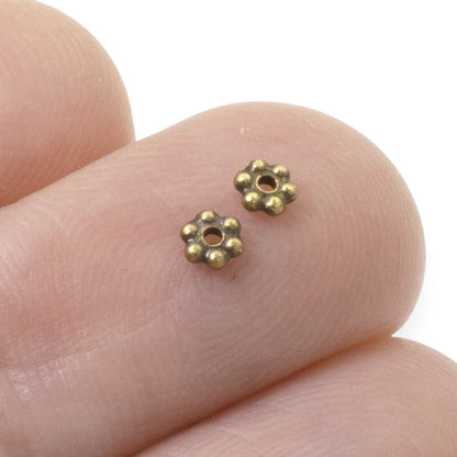 Hackberry Creek antique brass 3mm daisy spacer beads with 6 petals and a central hole, designed by TierraCast.