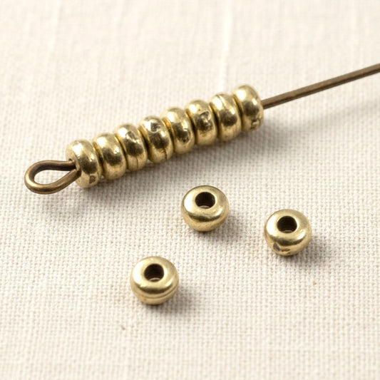 Hackberry Creek Antique Brass 3mm smooth heishi disk beads for boho jewelry making. Pack of 50.