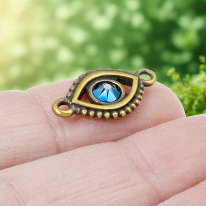 Hackberry Creek antique brass evil eye connector link with a central blue crystal for bohemian jewelry making.