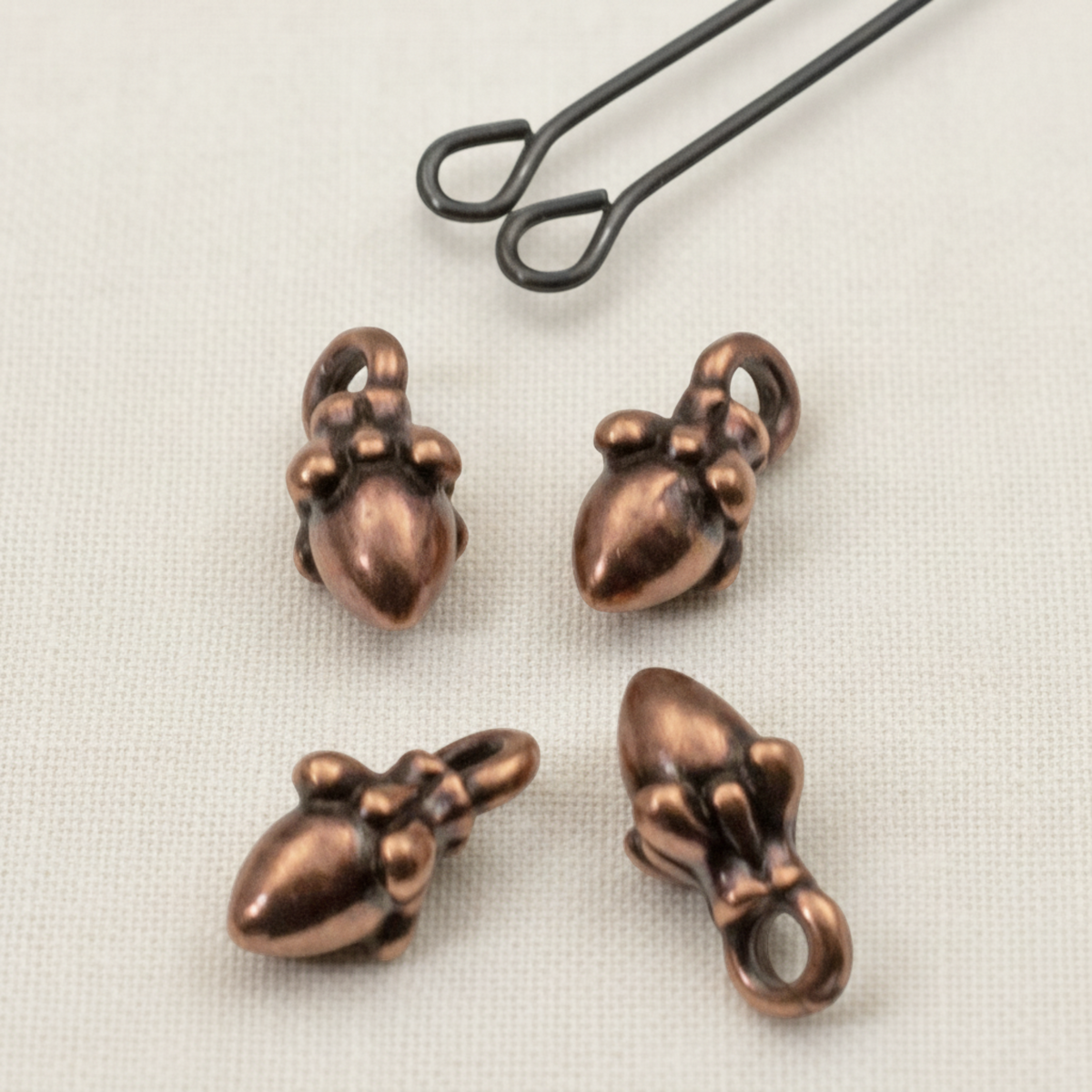 Hackberry Creek tiny 3D antique copper acorn charms for jewelry making, shown with a leather cord loop.