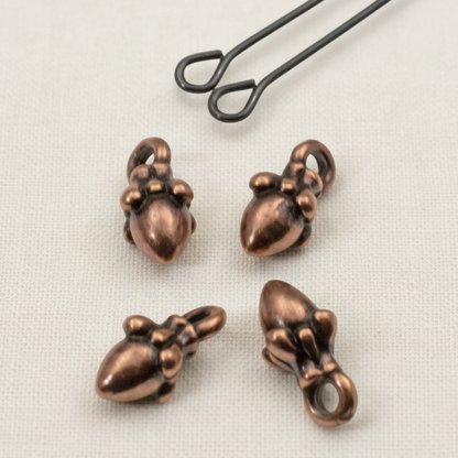 Hackberry Creek tiny 3D antique copper acorn charms for jewelry making, shown with a leather cord loop.