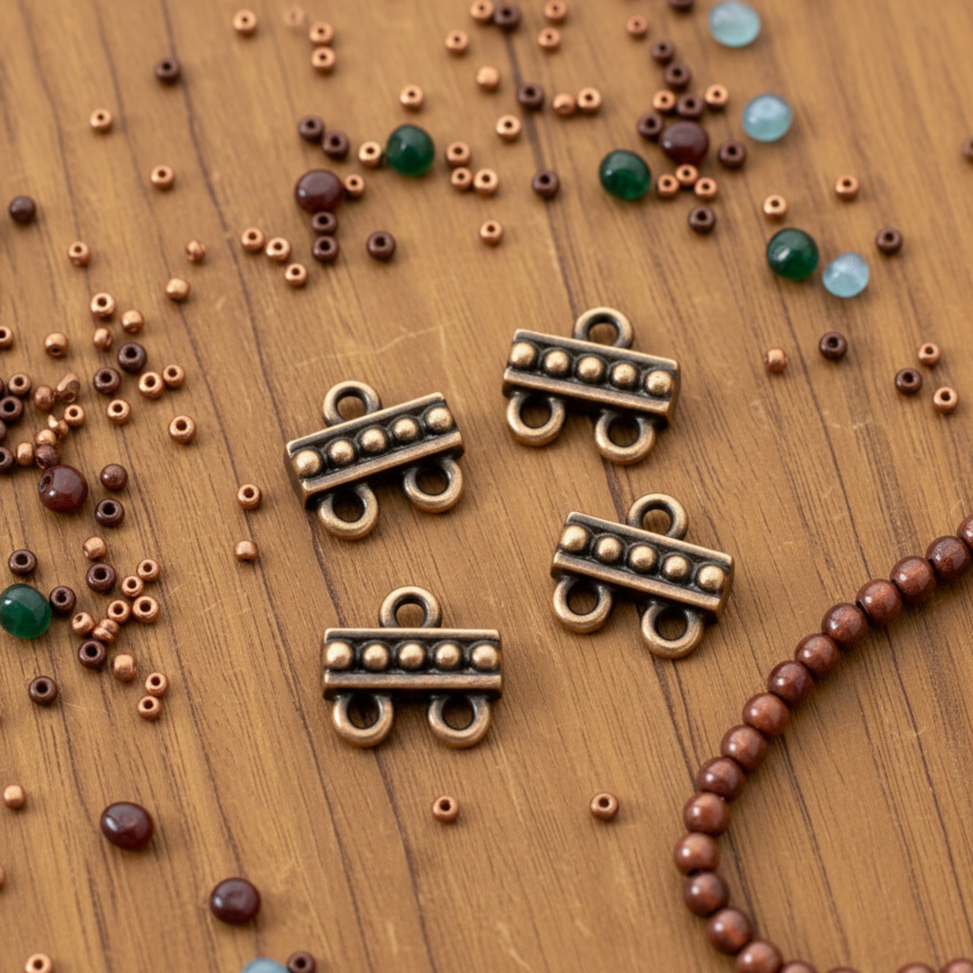 Hackberry Creek antique copper 2:1 beaded multi-strand jewelry connectors on a wooden surface with scattered beads.