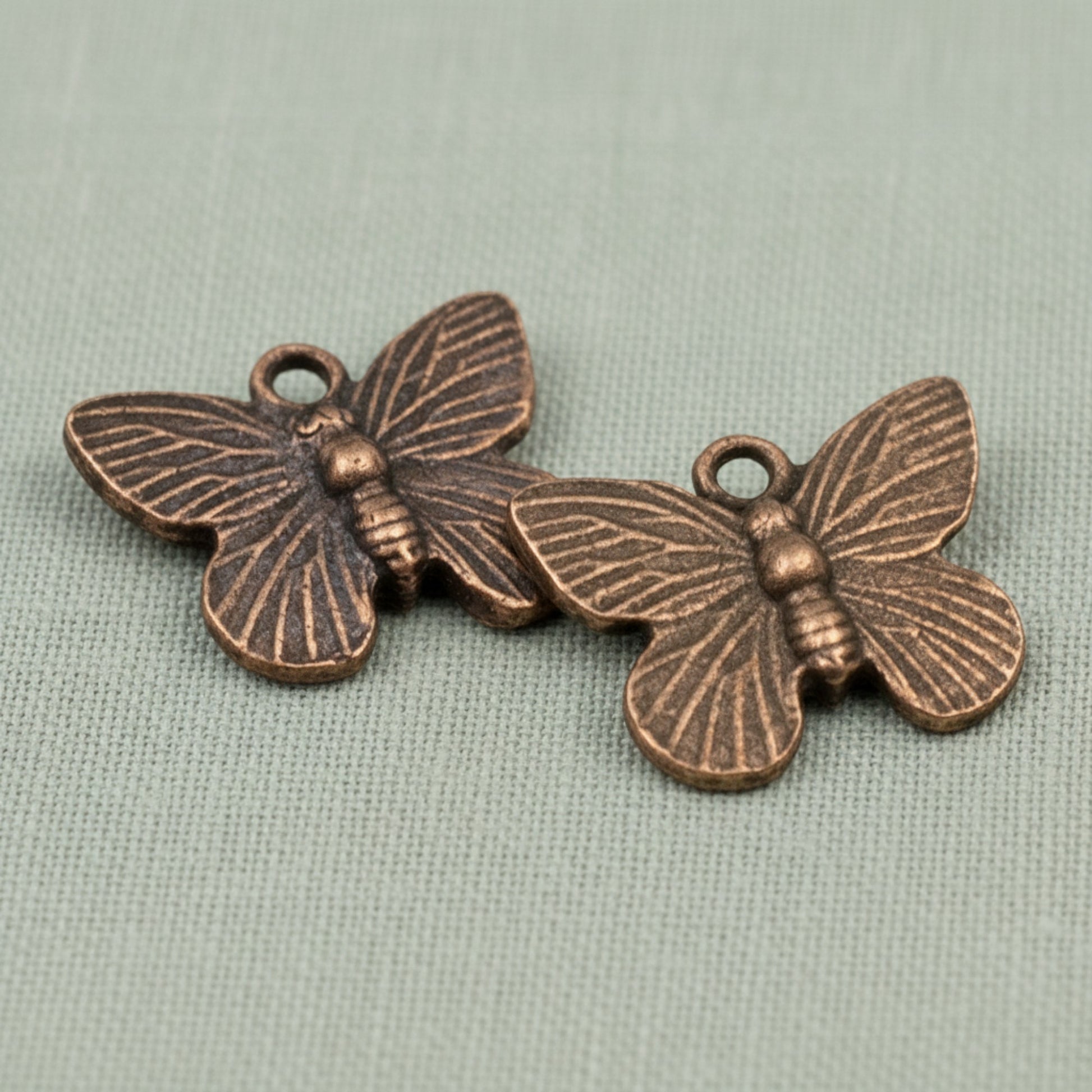 Hackberry Creek antique copper butterfly charms with detailed wing textures for jewelry making.