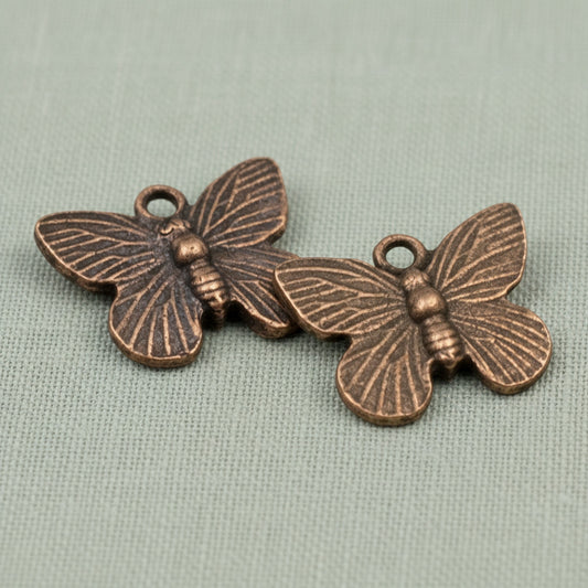 Hackberry Creek antique copper butterfly charms with detailed wing textures for jewelry making.