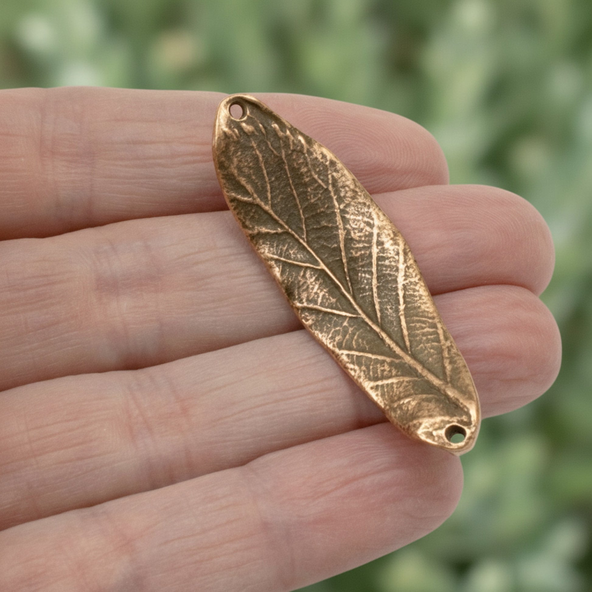 Hackberry Creek antique copper plated pewter leaf bracelet connector with organic detailing held in a hand.