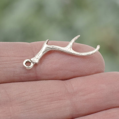 Hackberry Creek antique silver antler charm for jewelry making held on a fingertip