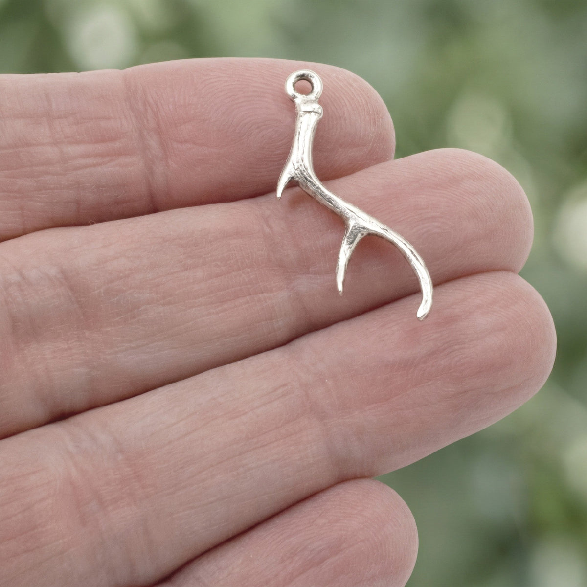 Hackberry Creek antique silver antler charm held in hand for jewelry making projects