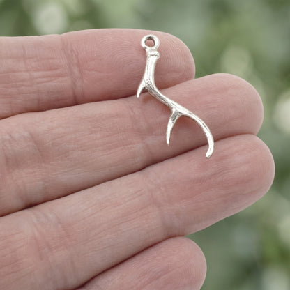Hackberry Creek antique silver antler charm held in hand for jewelry making projects