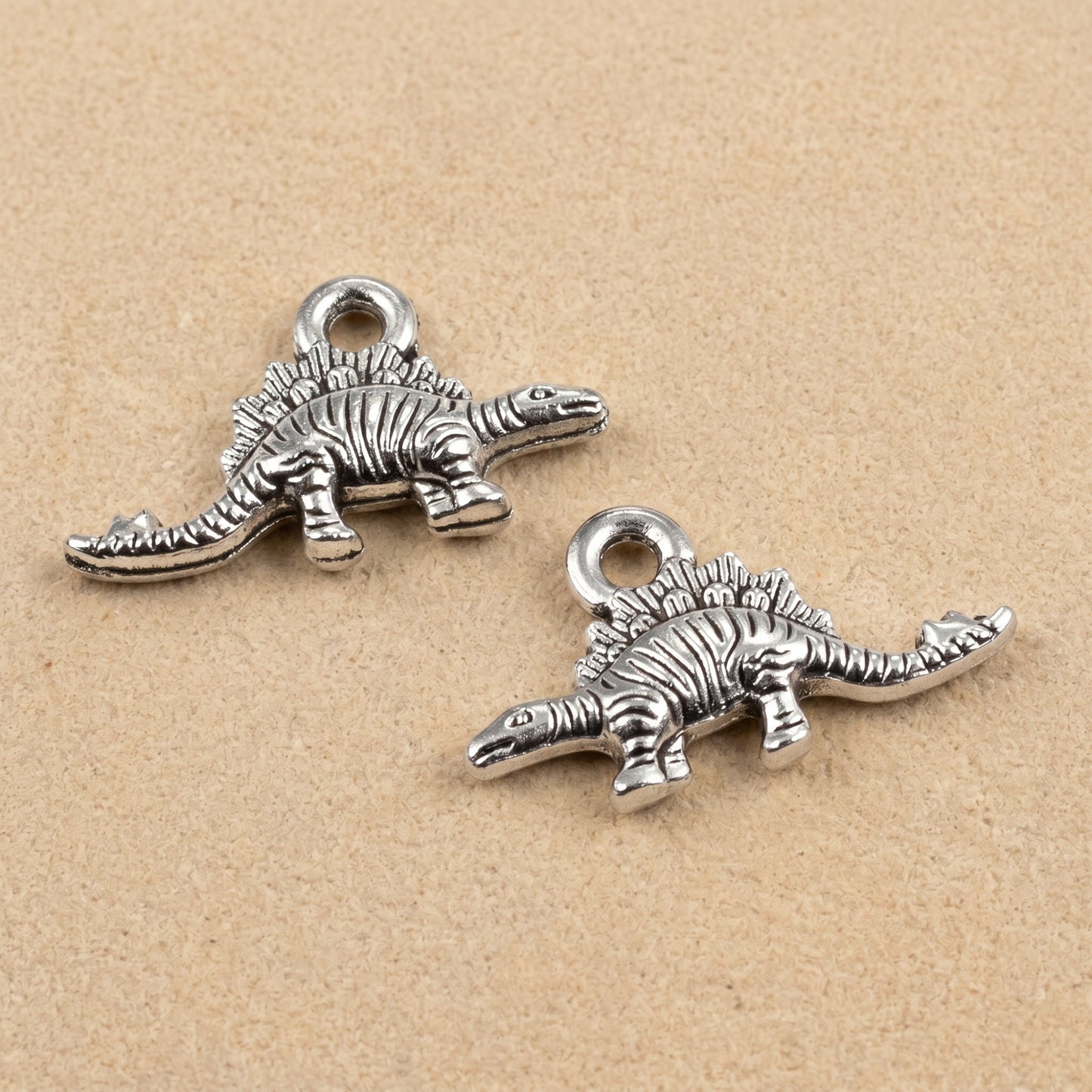 Hackberry Creek antique silver metal dinosaur charms for jewelry making, featuring detailed double-sided designs.