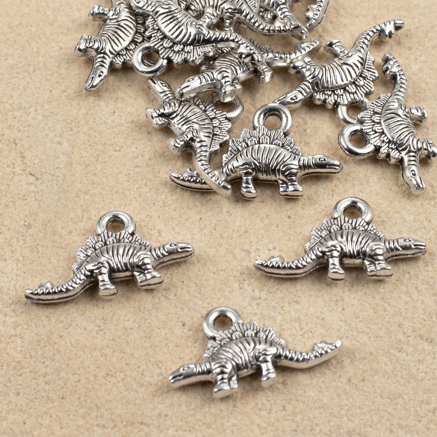Hackberry Creek antique silver dinosaur charms for jewelry making, featuring detailed double-sided metal pendants.