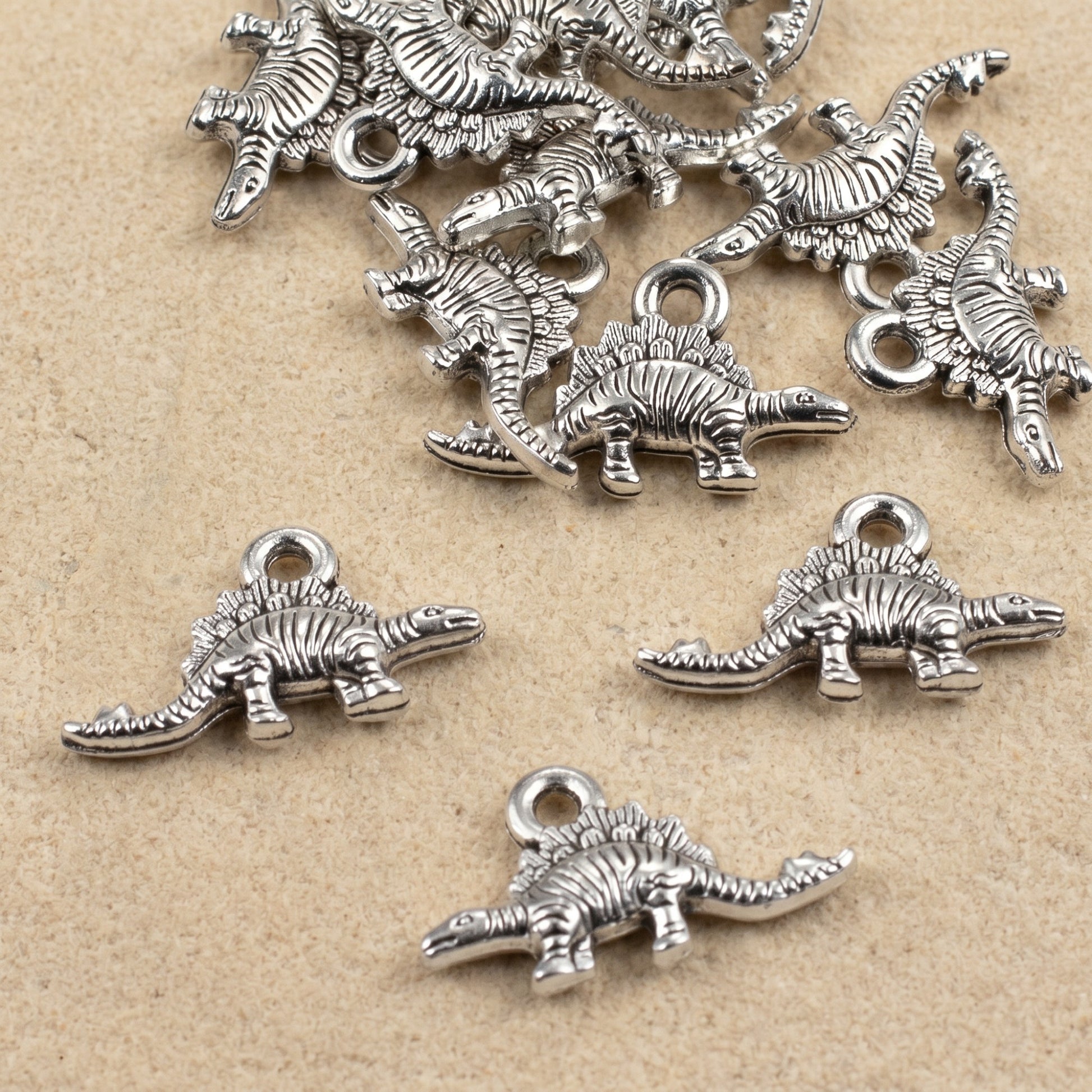 Hackberry Creek antique silver dinosaur charms for jewelry making, featuring detailed double-sided metal pendants.
