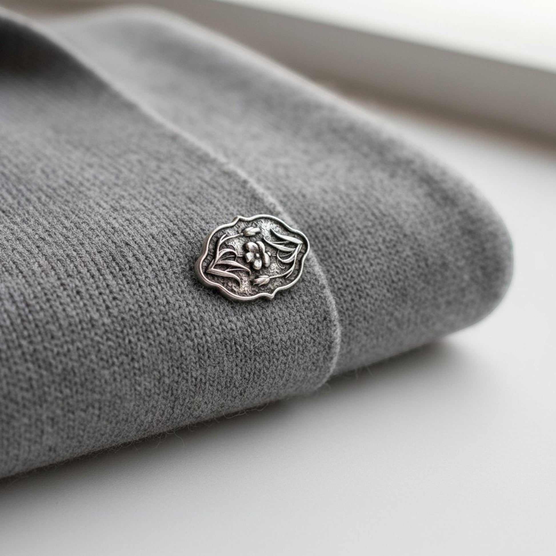 Hackberry Creek antique silver flower button clasp with detailed botanical motif attached to a grey knit fabric
