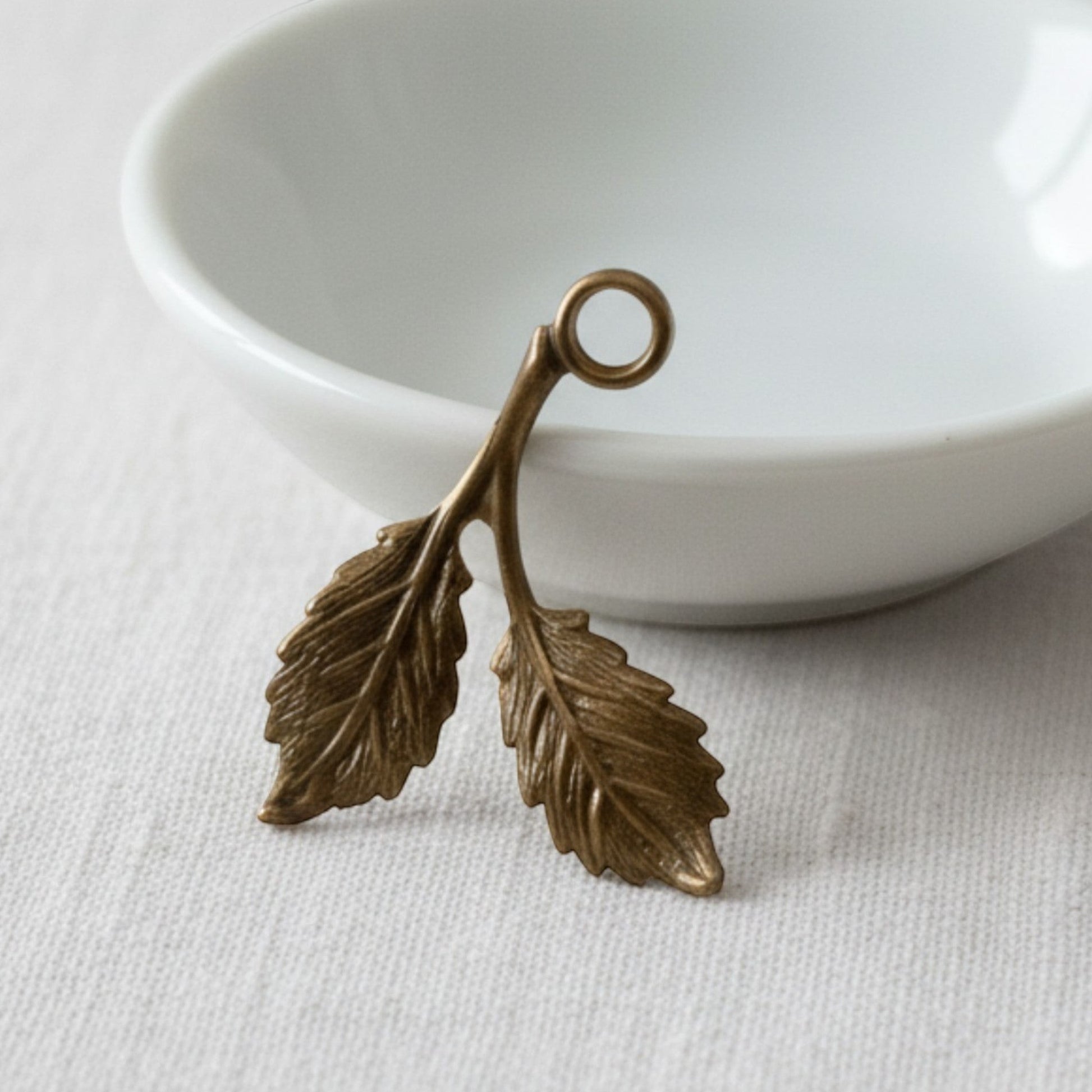 Hackberry Creek antiqued brass beech leaf charms with detailed botanical texture on both sides for jewelry making.