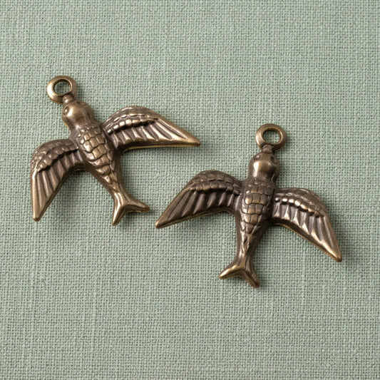 Hackberry Creek antiqued brass bird charms with detailed wings and concave design for cottagecore jewelry making.