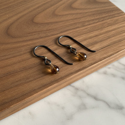 Hackberry Creek matte black niobium earring hooks with antique brass bead and faceted amber drop.