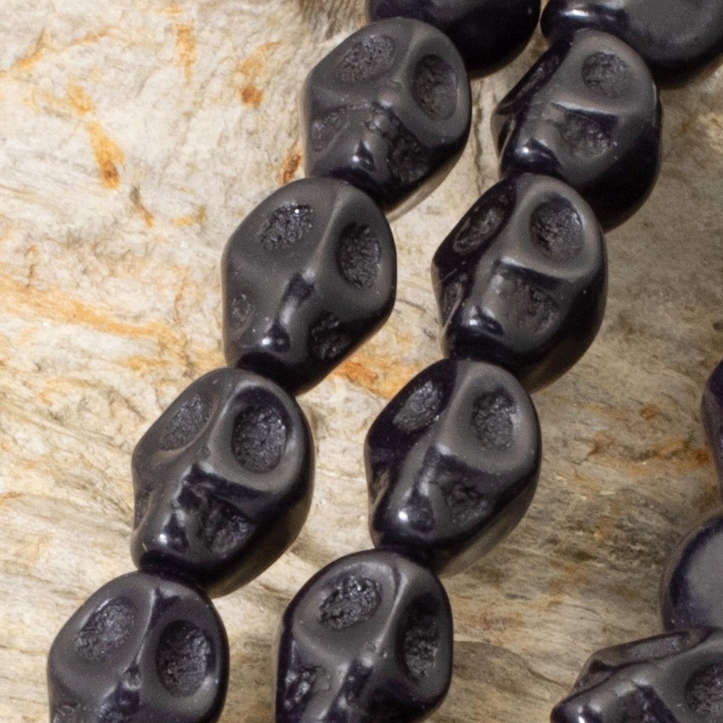 Hackberry Creek black magnesite skull beads on a 15-inch strand for DIY Halloween jewelry and craft projects.