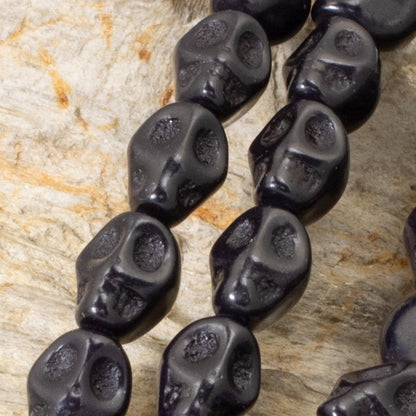 Hackberry Creek black magnesite skull beads on a 15-inch strand for DIY Halloween jewelry and craft projects.
