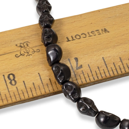 Hackberry Creek black magnesite skull beads on a wooden ruler for size reference
