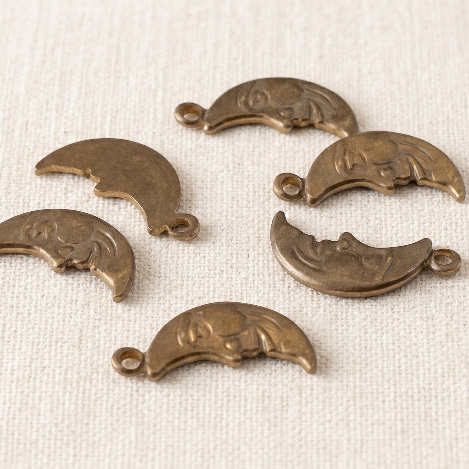 Hackberry Creek antiqued brass Man in the Moon crescent charms with detailed celestial faces for jewelry making.