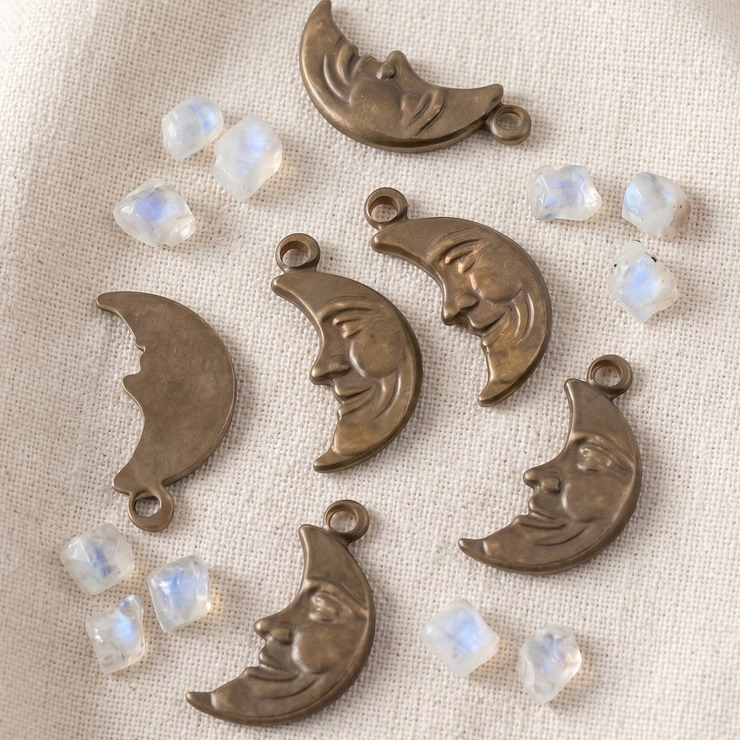 Hackberry Creek antiqued brass crescent moon charms with detailed faces, scattered with small moonstone beads.