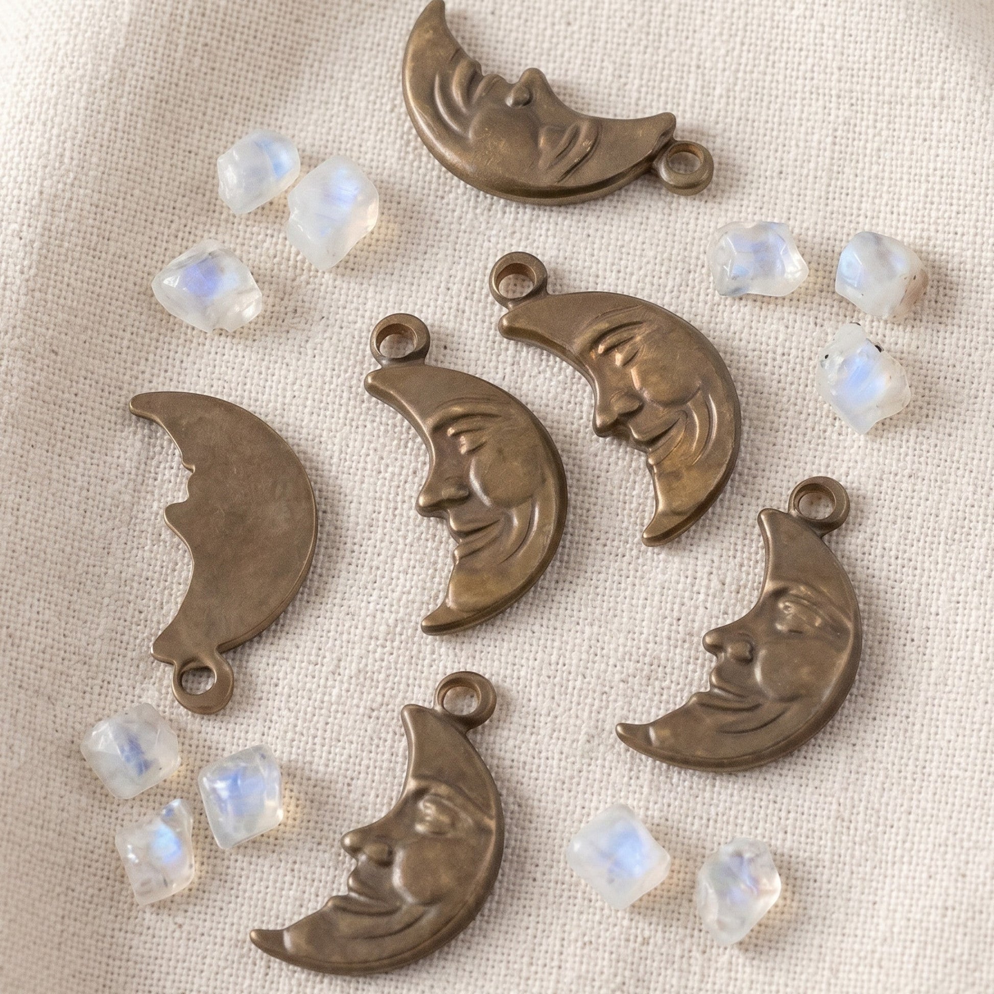 Hackberry Creek antiqued brass crescent moon charms with detailed faces, scattered with small moonstone beads.