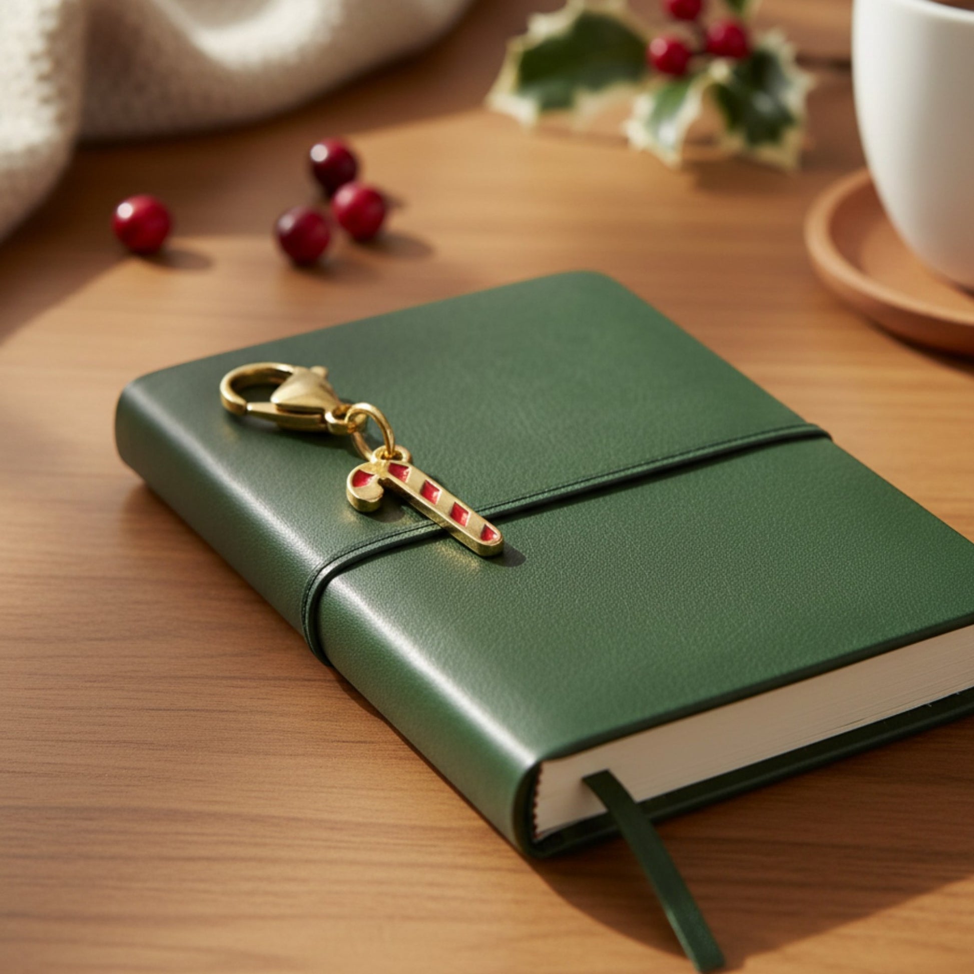 Hackberry Creek gold-plated candy cane charm with red stripes clipped onto a dark green leather notebook