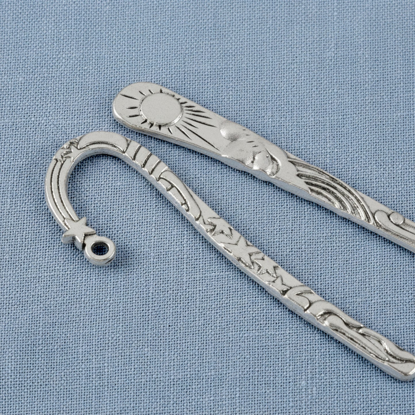 Hackberry Creek antique silver metal bookmarks featuring celestial sun and star designs on a blue fabric background.