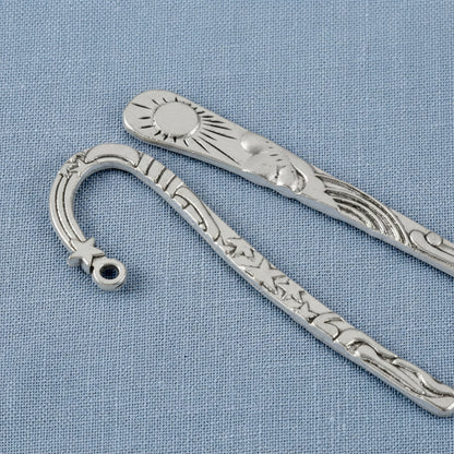Hackberry Creek antique silver metal bookmarks featuring celestial sun and star designs on a blue fabric background.