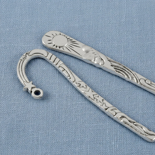 Hackberry Creek antique silver metal bookmarks featuring celestial sun and star designs on a blue fabric background.
