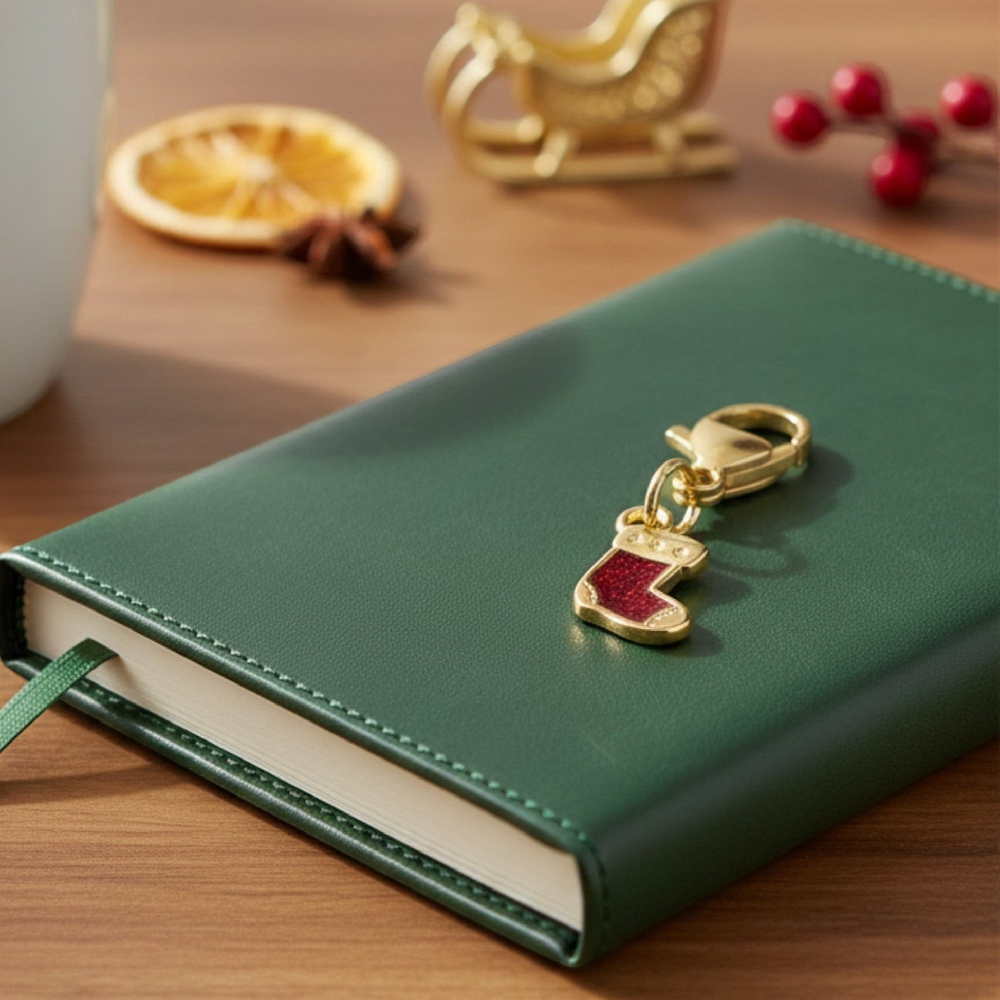 Hackberry Creek gold-plated Christmas stocking charm with red glitter enamel on a green notebook