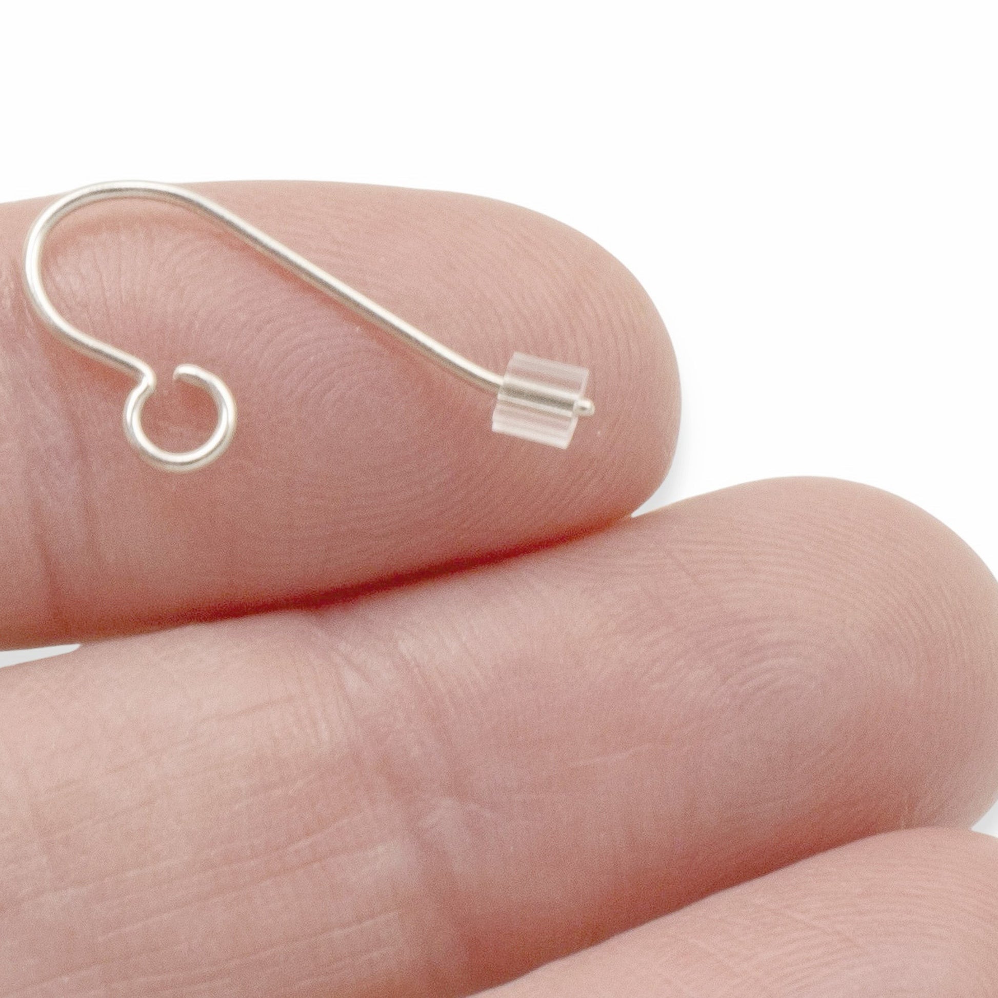 Hackberry Creek clear plastic ribbed earring backs on a finger, 3mm x 3mm, for French hook and post earrings.