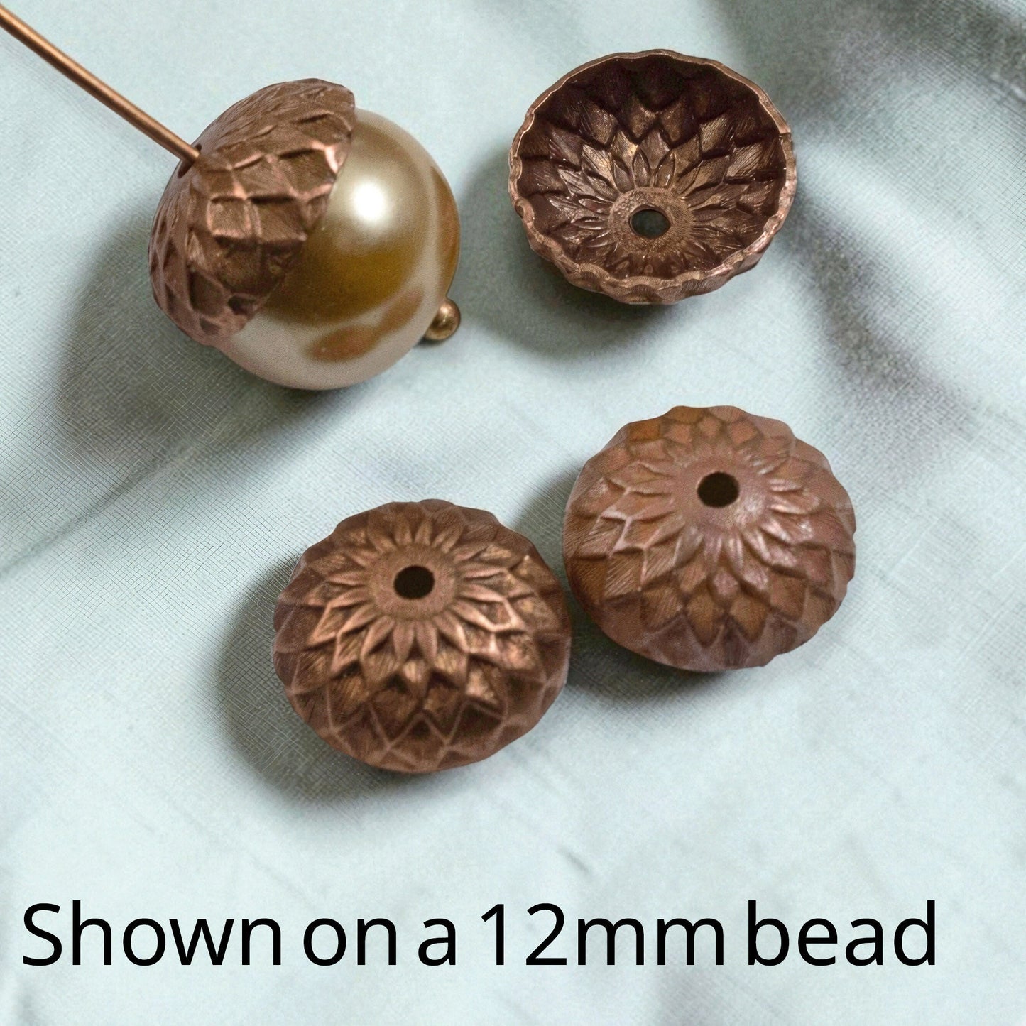 Hackberry Creek artisan copper acorn bead caps with sunflower petal relief design, shown with a 12mm round bead.