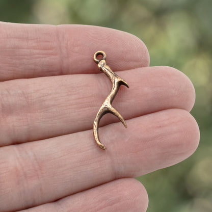 Hackberry Creek antique copper plated pewter antler charm held between fingers for jewelry making