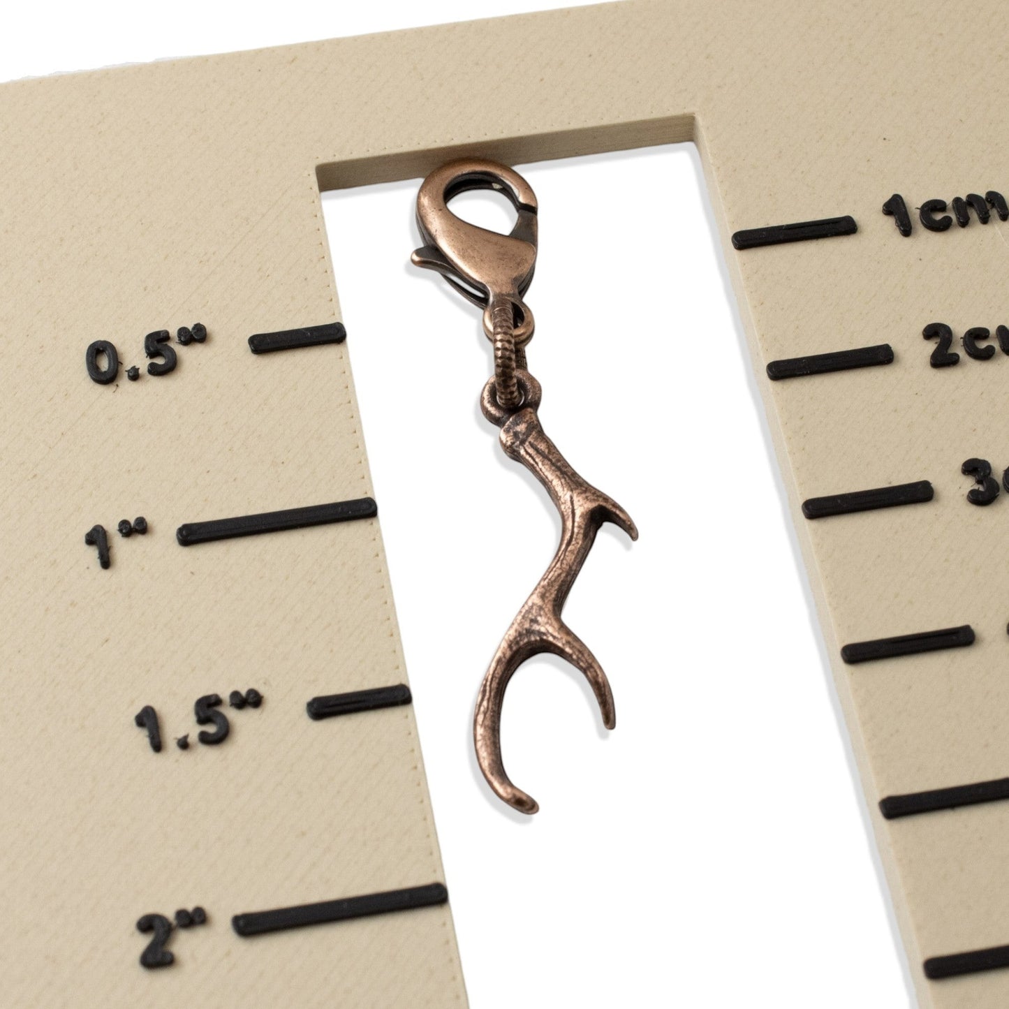 Hackberry Creek copper-plated pewter antler charm with a lobster clasp, shown against a scale for size reference.