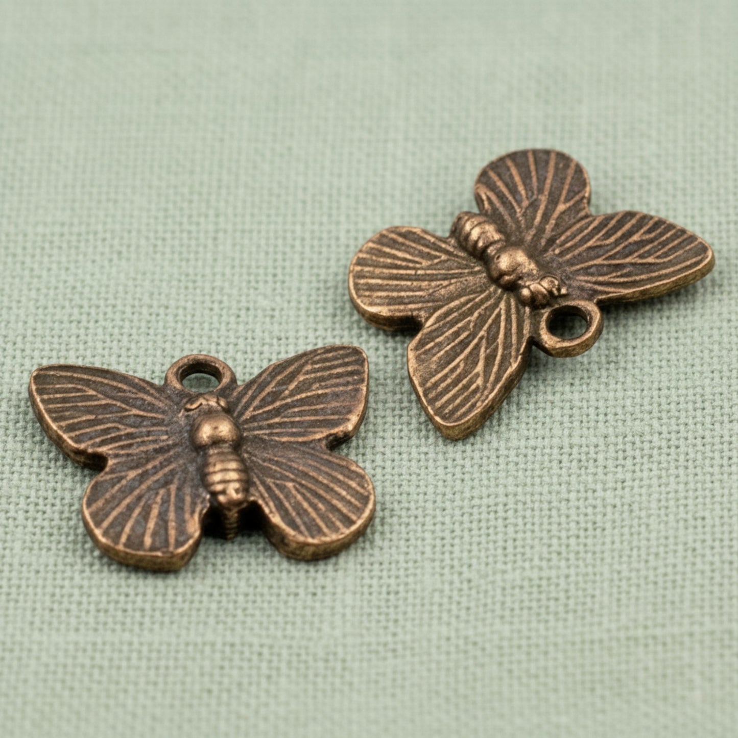 Hackberry Creek antique copper butterfly charms with detailed wing patterns for rustic jewelry making.