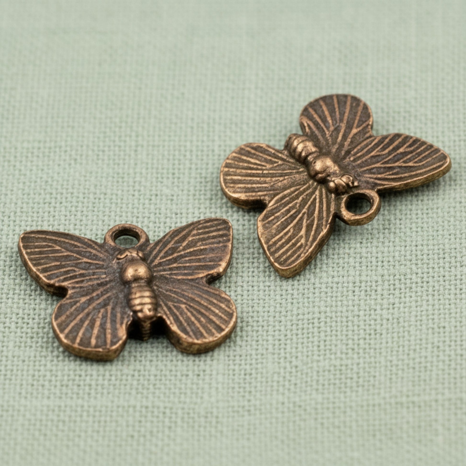Hackberry Creek antique copper butterfly charms with detailed wing patterns for rustic jewelry making.