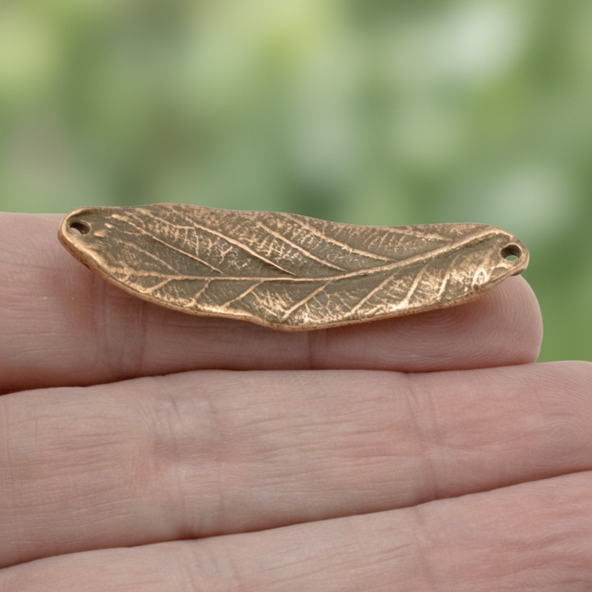 Hackberry Creek antique copper leaf bracelet connector link with organic textured detail held in a hand.