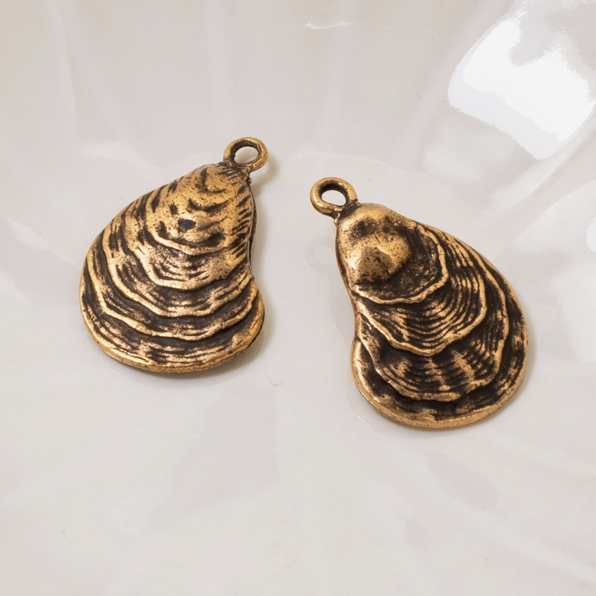 Hackberry Creek antique copper oyster shell charms with detailed ridges, perfect for coastal jewelry designs.