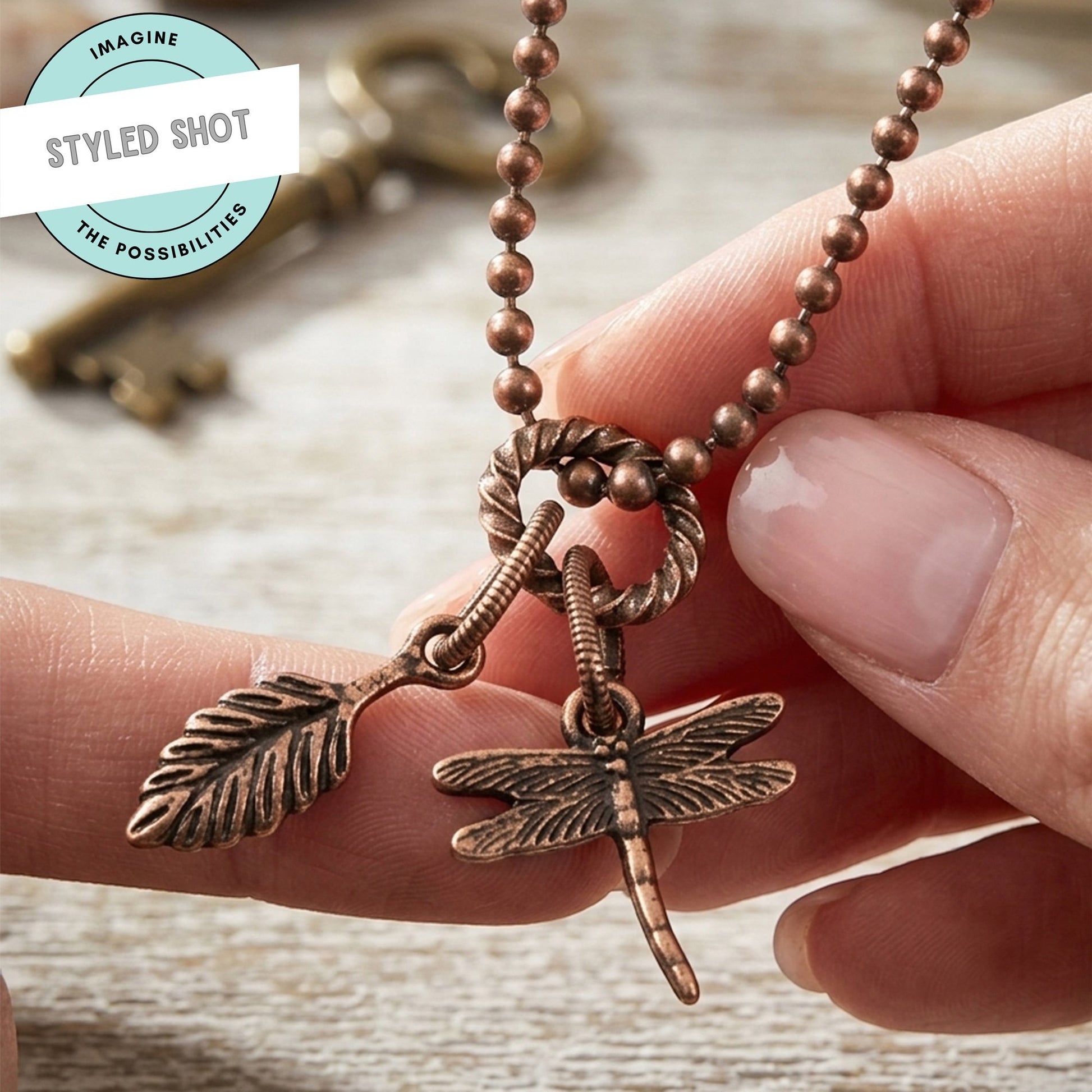 Hackberry Creek antique copper rope jump rings connecting a leaf charm and dragonfly charm on a beaded chain.