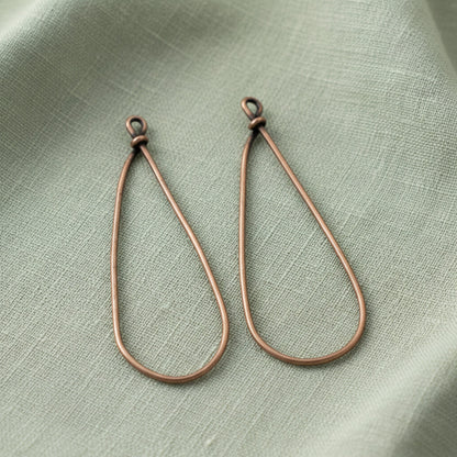 Hackberry Creek large copper teardrop earring frames for DIY jewelry making on a sage green linen background.