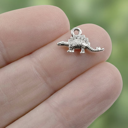 Hackberry Creek tiny antique silver dinosaur charm held between fingers for scale, showing detailed metal texture.