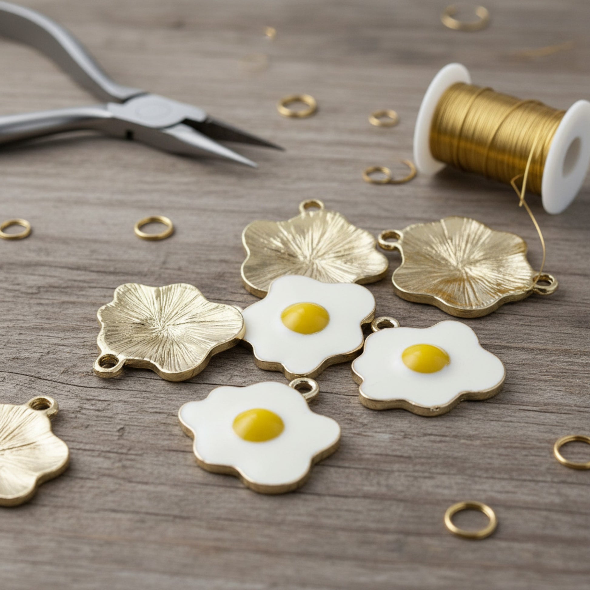 Hackberry Creek enamel fried egg charms with light gold metal backing for DIY jewelry making on a wooden surface.